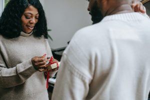 woman opening gift from man facing her