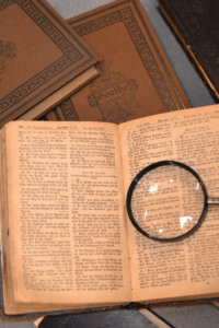brown colored papers and books with a magnifying glass on top of an open book.